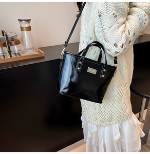 Gros plan du sac seau en cuir verni noir avec détails argentés sur une table
