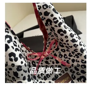 Macro detail of leopard canvas tote featuring a pink checkered bow and leather label