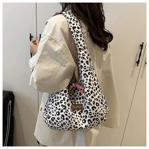 Detail of leopard print tote bag featuring a leather Fashion tag and pink plaid ribbon