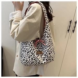 Detail of leopard print tote bag featuring a red ribbon bow and Fashion leather label