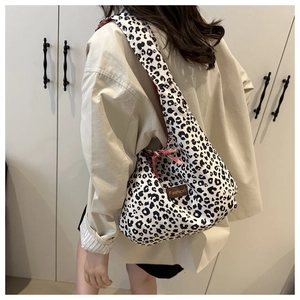 Detail of leopard print tote bag with brown leather label and red ribbon accent