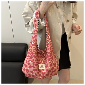 Close-up of pink leopard print canvas tote bag with woven brand label on model