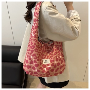 Detailed close-up of a pink leopard print oversized tote bag worn by a model in a room