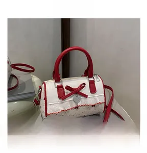 Detail of mini Boston bag featuring red polka dots, bow accent and heart charm detail