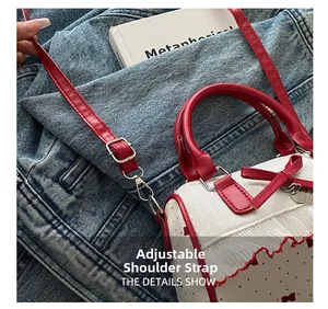 Detail of adjustable red leather shoulder strap with silver buckle and heart pendant charm