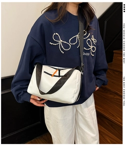 Dettaglio della borsa a tracolla in nylon bianco con cinturino nero e zip arancione
