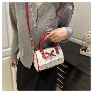Detail view of mini Boston bag with red polka dots, bow accents, and lace trim details