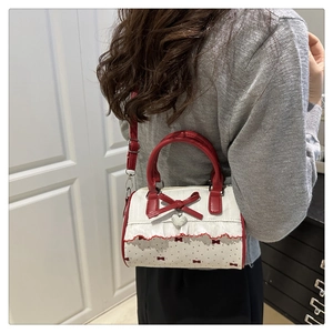 Detail of red and white polka dot Boston bag featuring lace trim and heart charm