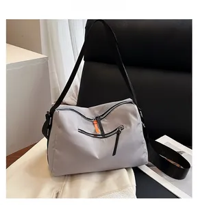 Detail view of grey utility crossbody bag with multi-zipper pockets and orange accents