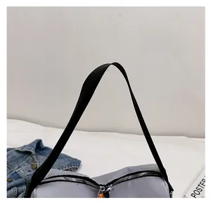 Detail of wide black woven strap and silver dual zipper on grey nylon crossbody bag