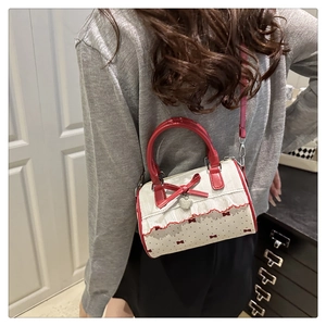 Dettaglio charm a cuore su borsa a pois con bordo in pizzo bianco e manico rosso