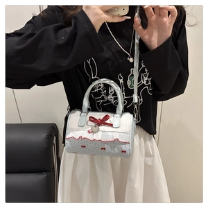 Détail du sac Boston avec nœud, volants et pendentif cœur en bleu clair et crème doux