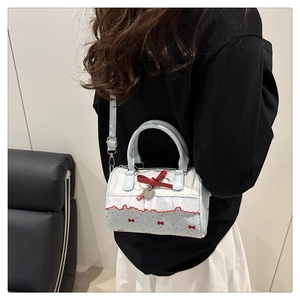 Vista modella della borsa a cilindro blu a pois con fiocco rosso e ciondolo a cuore