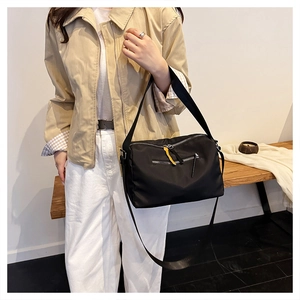Detail of high-density nylon crossbody bag featuring adjustable strap and yellow zipper pull