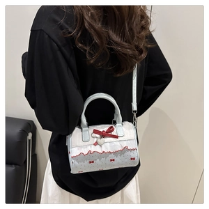 Detail of Boston bag featuring red 3D bow, lace trim and heart pendant accessories