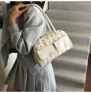 Detail view of stylish cream Boston bag with cute cartoon bear prints and front pockets