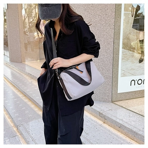 Dettaglio della borsa a tracolla in nylon viola chiaro con cinturino nero e zip arancione