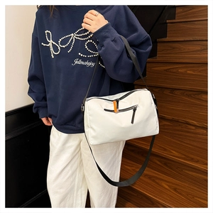 Dettaglio borsa a tracolla in nylon bianco con spalline nere e tiralampo arancioni a contrasto