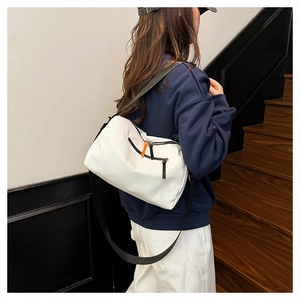 Dettaglio borsa a tracolla in nylon bianco con cerniera arancione e tracolla nera su modello