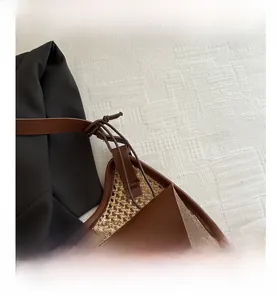 Detail shot of hand-woven straw texture and brown leather trim on the shoulder bag