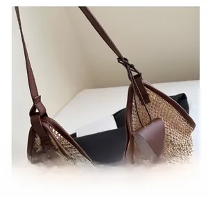 Detail of straw woven tote with brown leather straps and hanging decorative pendant