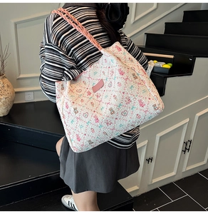 Gros plan d'un sac cabas floral avec anses roses et motifs d'ours porté par un mannequin