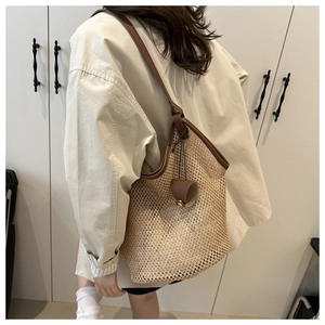 Detail of hand-woven straw tote with premium brown leather straps on model shoulder