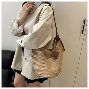 Detail of a large woven tote bag with brown leather handles and a side-view perspective
