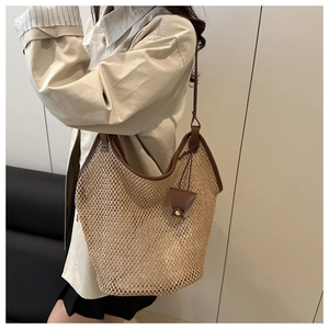 Detailed side view of beige woven straw tote bag with brown leather trim and small pouch