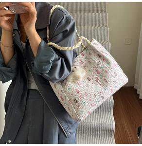 Close-up of quilted floral tote bag with cute bear charm and woven rope handle detail