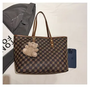 Detail of checkered tote bag with Z-pattern print, leather straps and bear charm