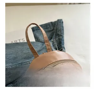 Vue détaillée de la poignée en cuir souple et de la fermeture éclair du sac à dos rose