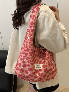 Borsa tote in tela con stampa leopardata rosa, chiusura a coulisse e tracolla indossata