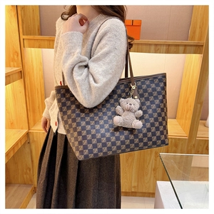 Detail view of large dark brown checkered tote bag with plush bear charm for daily commute