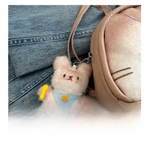Gros plan du pendentif ours en peluche avec bandana bleu sur un sac à dos rose