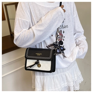 Detail of black and white checkered crossbody bag with silk scarf on the strap