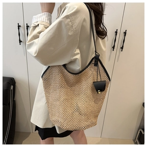Detail of woven straw tote bag with black faux leather trim and shoulder strap