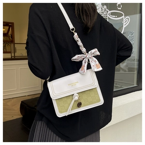 Detail of green checkerboard crossbody bag with white leather flap and silk scarf accent