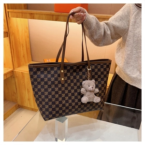 Detail of checkered tote bag with Z patterns and a cute plush bear charm decoration