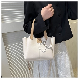 Detail of white leather tote bag with khaki handles and cute rabbit charm accessory