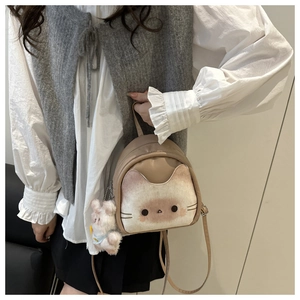 Detail of cute cat-shaped khaki leather backpack with a plush bear charm on the strap