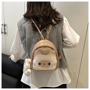 Close-up of cute cat pattern on brown PU leather backpack with soft white pompom charm