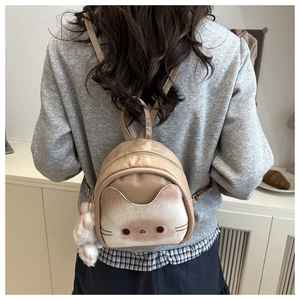 Detail of cute cat-shaped beige backpack with 3D ears and soft plush ball charm