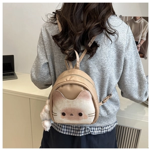 Detail showing plush cat face design on khaki backpack with 3D ears and fur ball charm