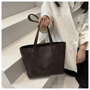 Detail of vintage coffee tote bag featuring oil wax leather texture and embossed logo