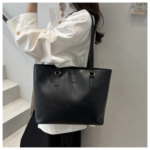 Close-up of black leather tote bag with metal rings and embossed fashion logo detail