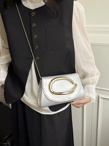 Chic silver crossbody bag with a large gold oval buckle and metal chain strap for women