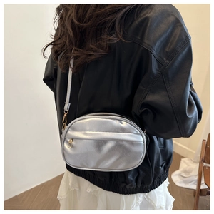 Silver metallic PU oval crossbody bag shown on model with adjustable strap and zipper detail