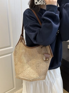 Large woven straw tote bag with brown leather trim and shoulder straps for summer beach use