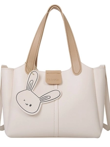 Minimalist cream tote bag with khaki handles and cute rabbit charm on white background